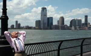 Un uomo ben vestito esegue esercizi di stiramento sulla banchina del fiume Hudson a New York